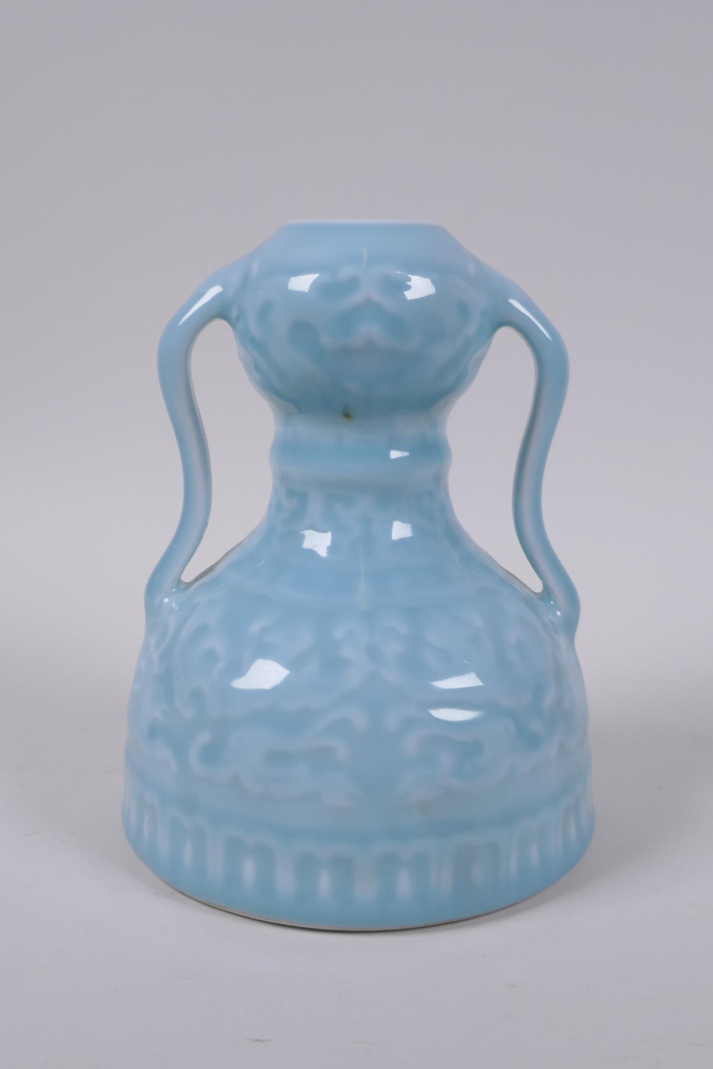 A celadon glazed porcelain two handled garlic head shaped vase with stylised under glaze dragon