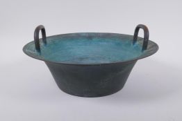 An antique Chinese bronze two handled spouting bowl with dragon decoration, 30cm diameter