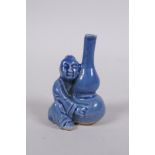 A Chinese blue glazed porcelain stem vase in the form of a seated figure holding a double gourd, 6cm