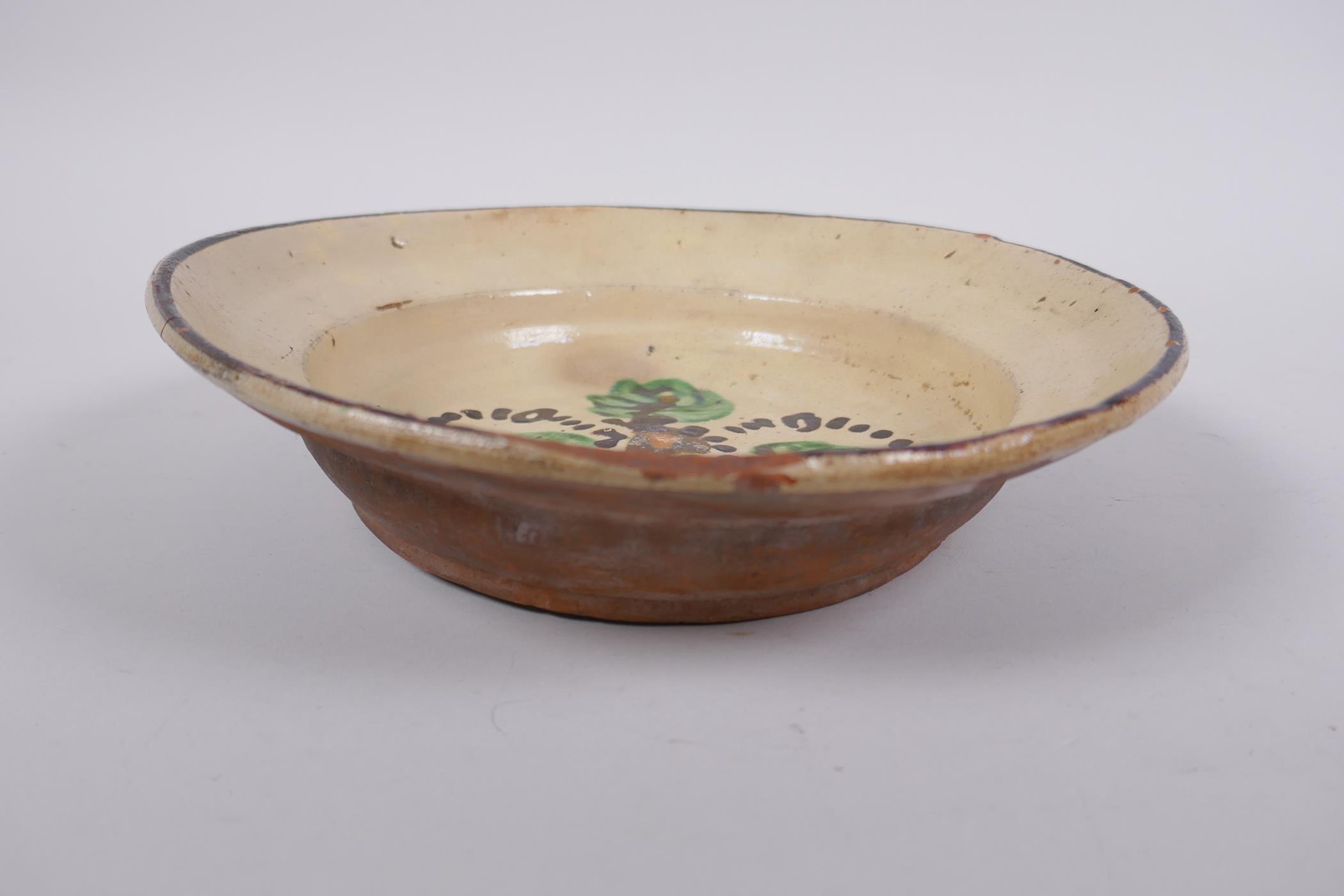 An antique Spanish terracotta dish with a faience glaze and floral decoration, AF repair, 21cm - Image 2 of 6