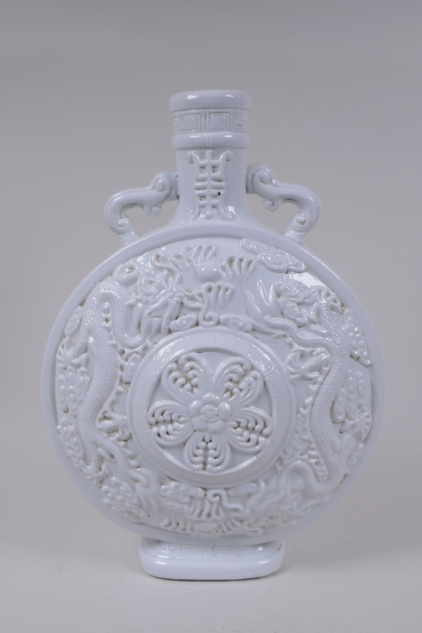 A Chinese blanc de chine porcelain two handled moon flask with raised and floral decoration,