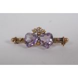 A Victorian yellow metal sweetheart brooch, set with seed pearls and two heart shaped amethysts,