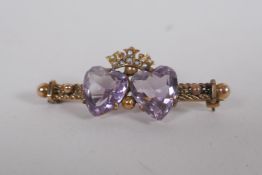 A Victorian yellow metal sweetheart brooch, set with seed pearls and two heart shaped amethysts,