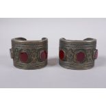 A pair of Turkmen white metal bangles set with red semi precious stones, 8 x 6cm