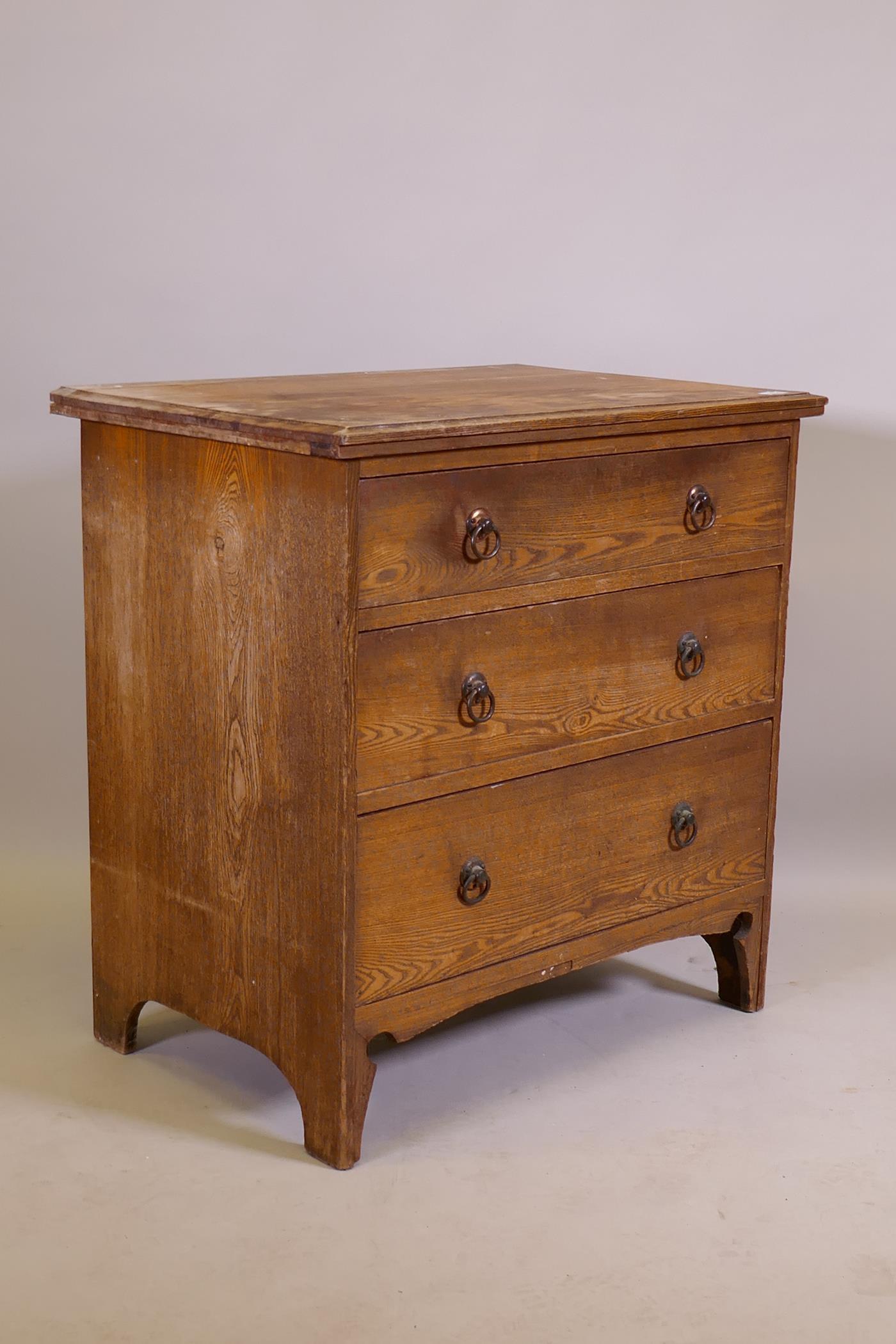 An Arts & Crafts oak three drawer chest, raised on shaped supports, 74 x 49 x 77cm