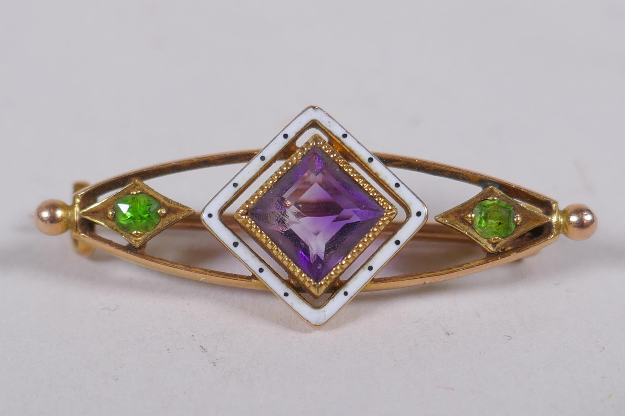 A 15ct gold suffragette brooch set with an amethyst and peridot, and enamel decoration, 3cm long, 3g