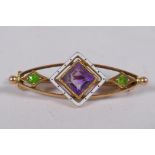 A 15ct gold suffragette brooch set with an amethyst and peridot, and enamel decoration, 3cm long, 3g