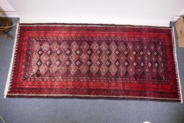A full pile hand woven red ground carpet with a geometric floral design, 268 x 130cm