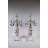 A pair of continental porcelain four branch candelabra decorated with putti, 59cm high