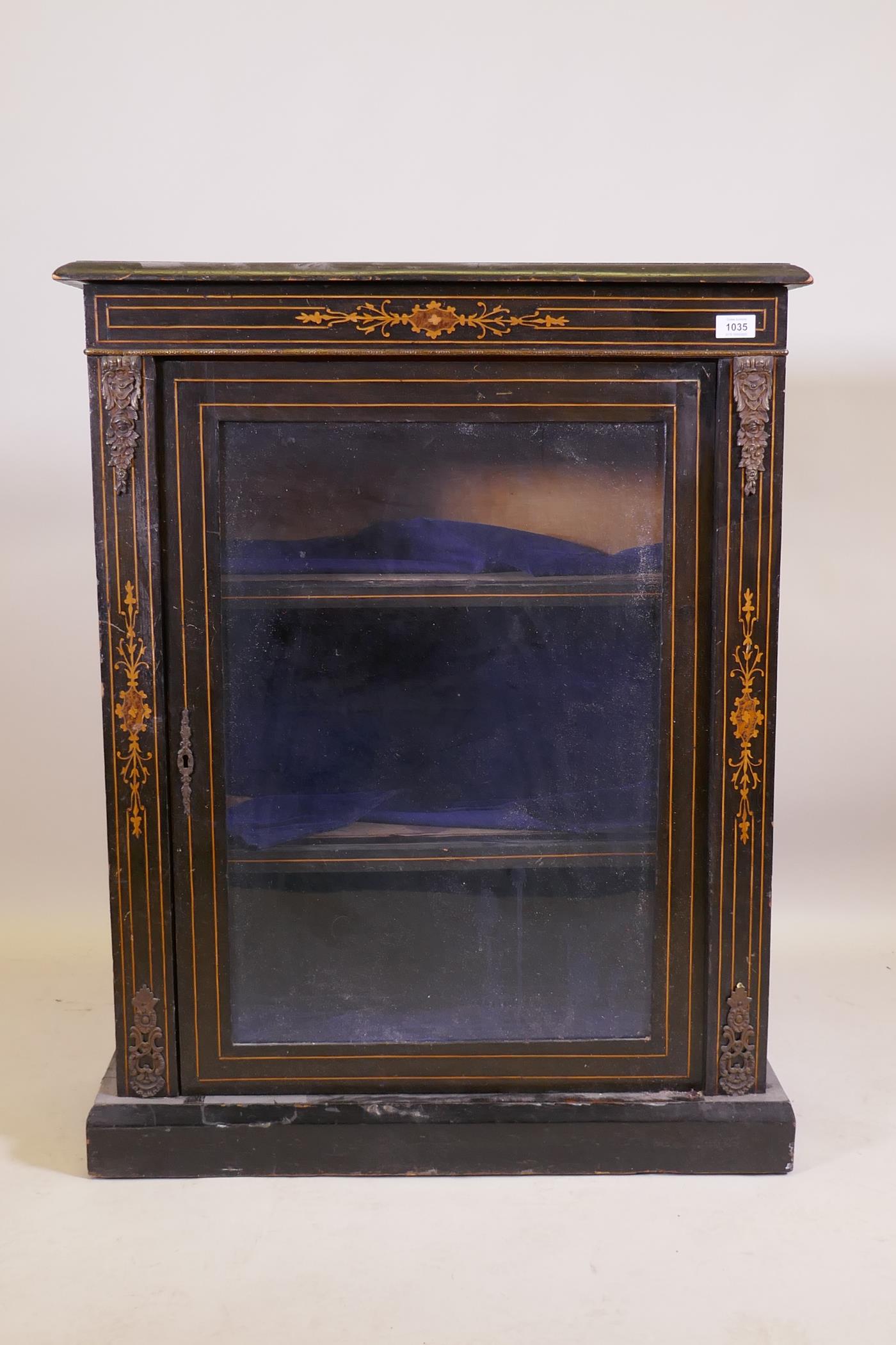 A Victorian ebonised and inlaid pier cabinet with brass mounts and single glazed door, raised on a