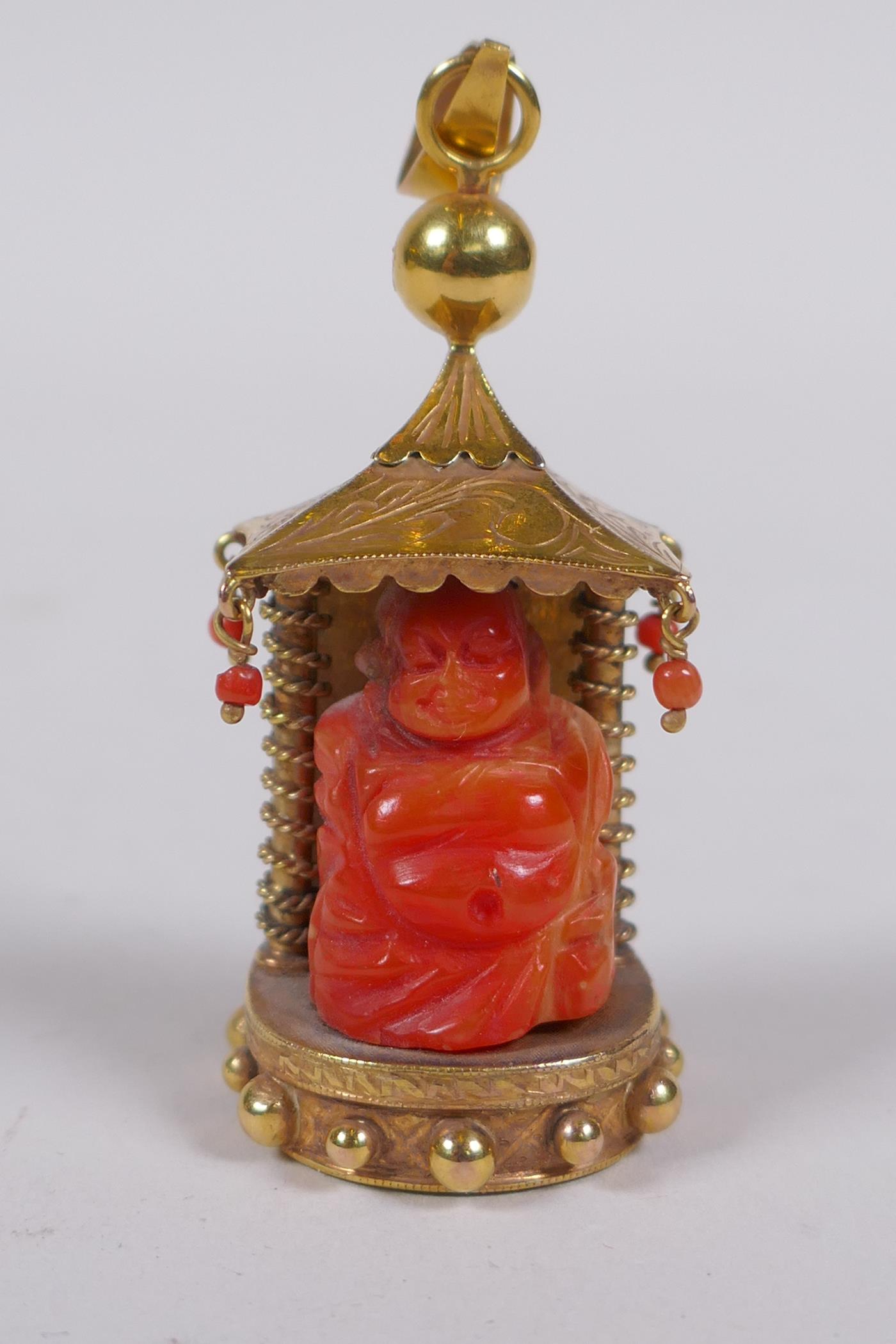 A 9ct gold pendant in the form of a shrine with carved coral figure of Buddha, 22.2g gross