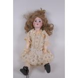 An antique German Schoenau and Hoffmeister bisque headed doll in a white lace dress, marked S PB H