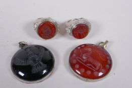 Two Islamic white metal intaglio rings and two similar pendants, largest 4cm diameter
