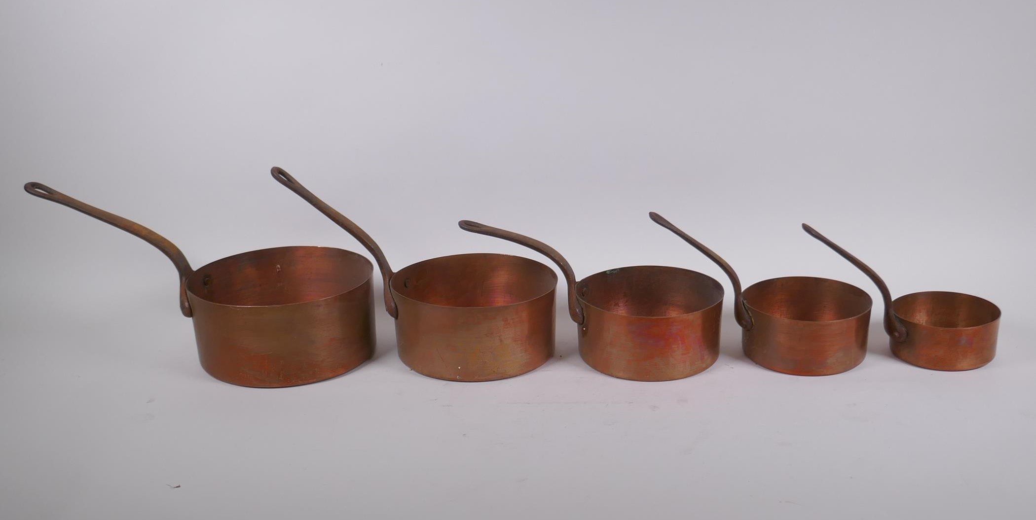 A set of five graduated copper sauce pans, largest 15cm diameter