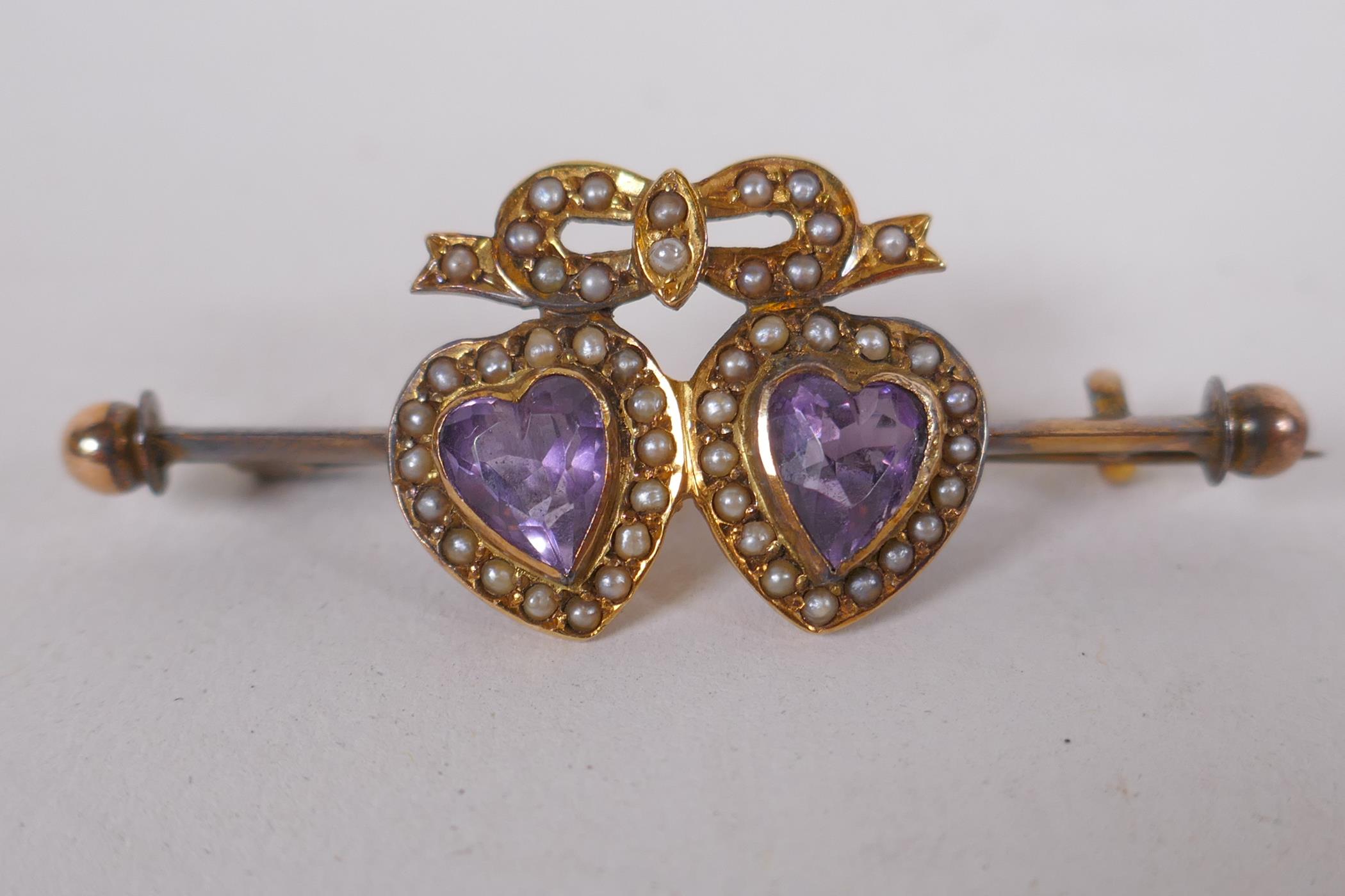 A 9ct gold brooch set with two heart shaped amethysts and seed pearls, 4.2cm long, 3.8g