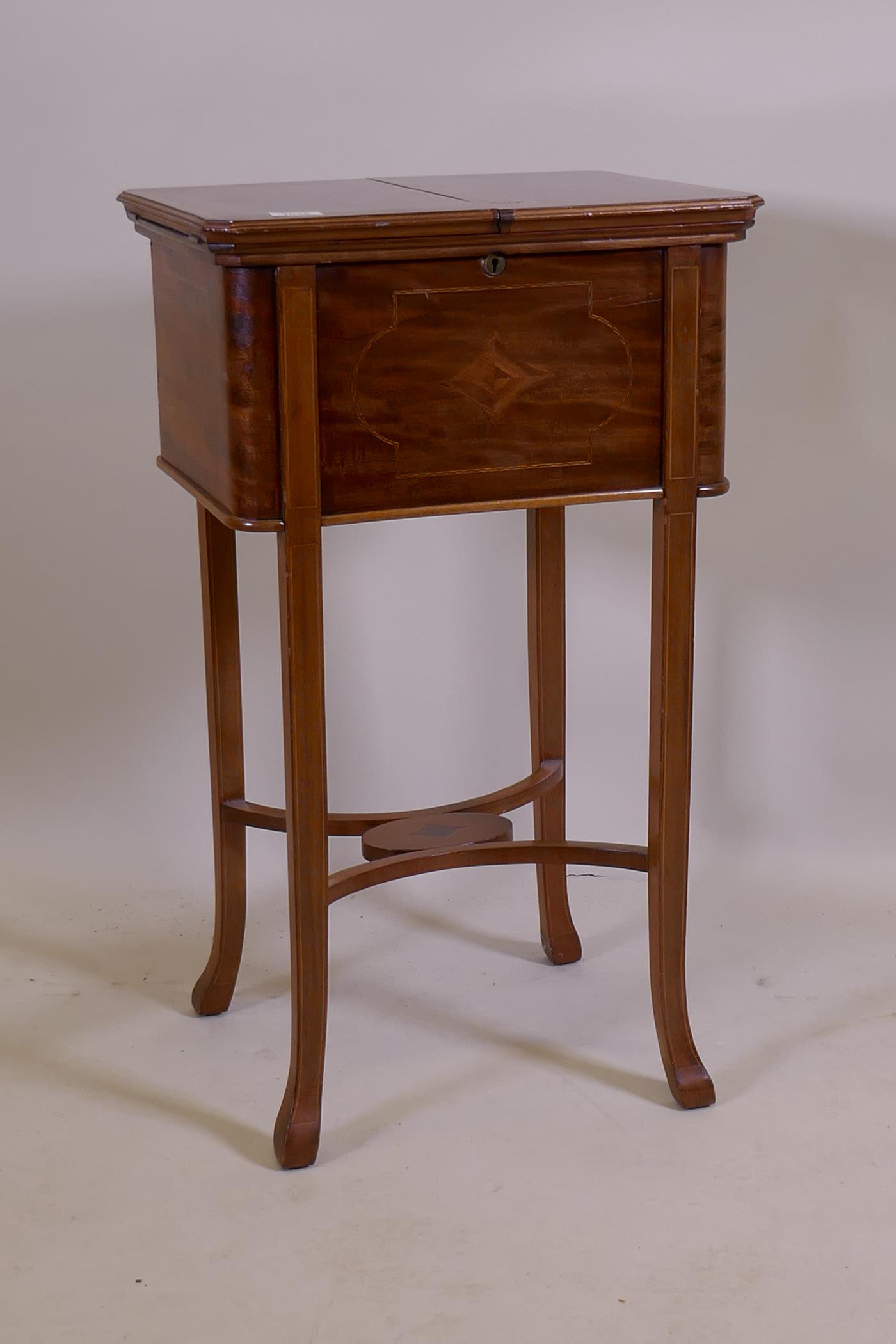 An Edwardian inlaid mahogany work table, the fold over top opening to reveal a fitted interior