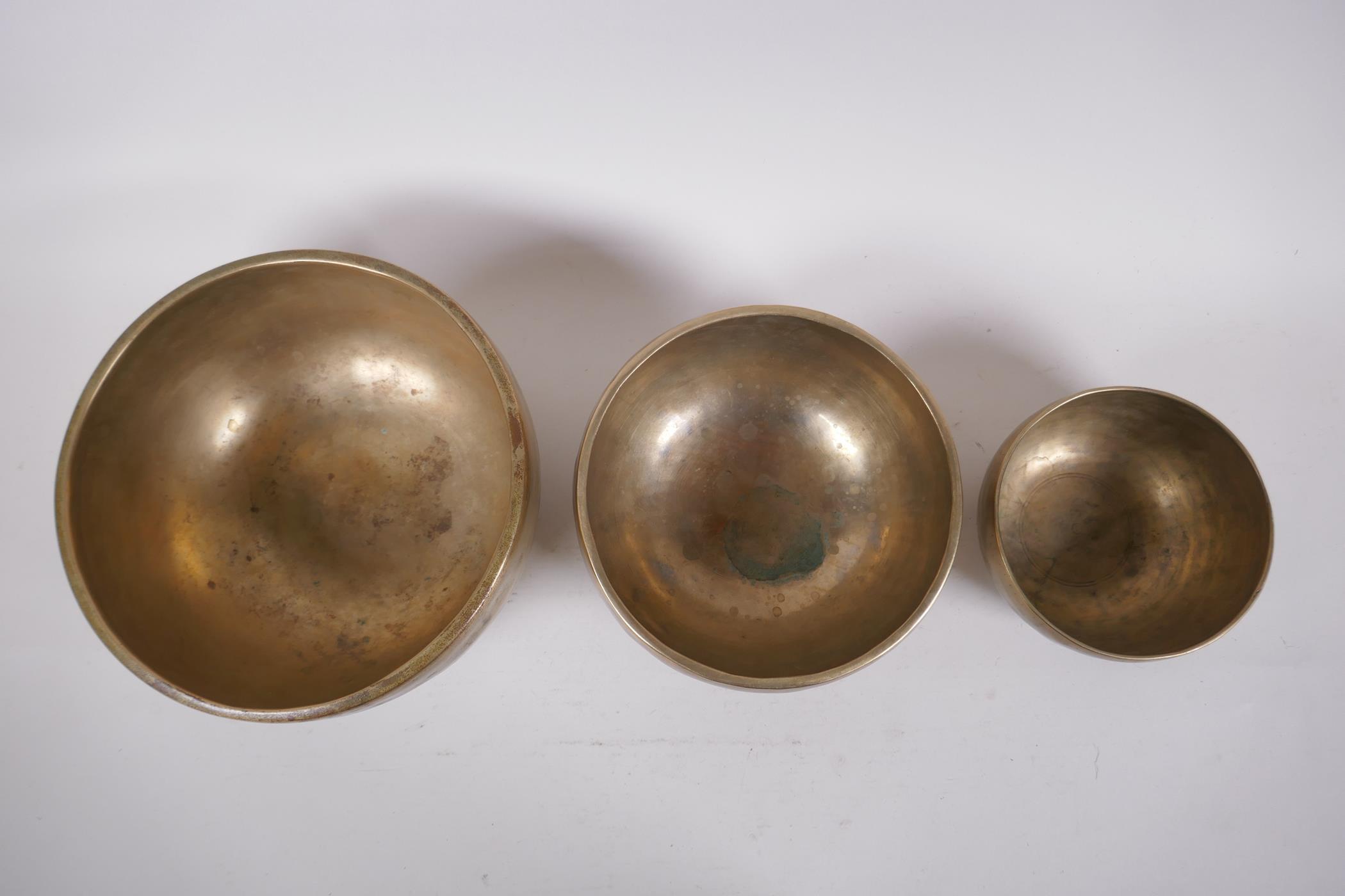 Three Tibetan graduated polished bronze singing bowls with hammered finish, and two wood hammers, - Image 3 of 5