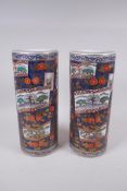 A pair of Japanese blue ground porcelain cylinder vases with decorative panels depicting landscape