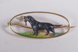 A 15ct yellow gold hunting brooch with overlaid enamel decoration of a gun dog carrying game, the