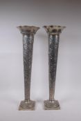 A pair of continental white metal trumpet shaped vases with repousse vine decoration and frilled