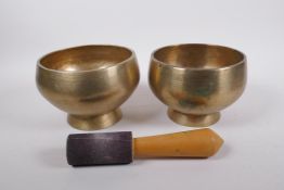A pair of Tibetan polished bronze footed singing bowls, with wood hammer, 12cm high x 19cm diameter