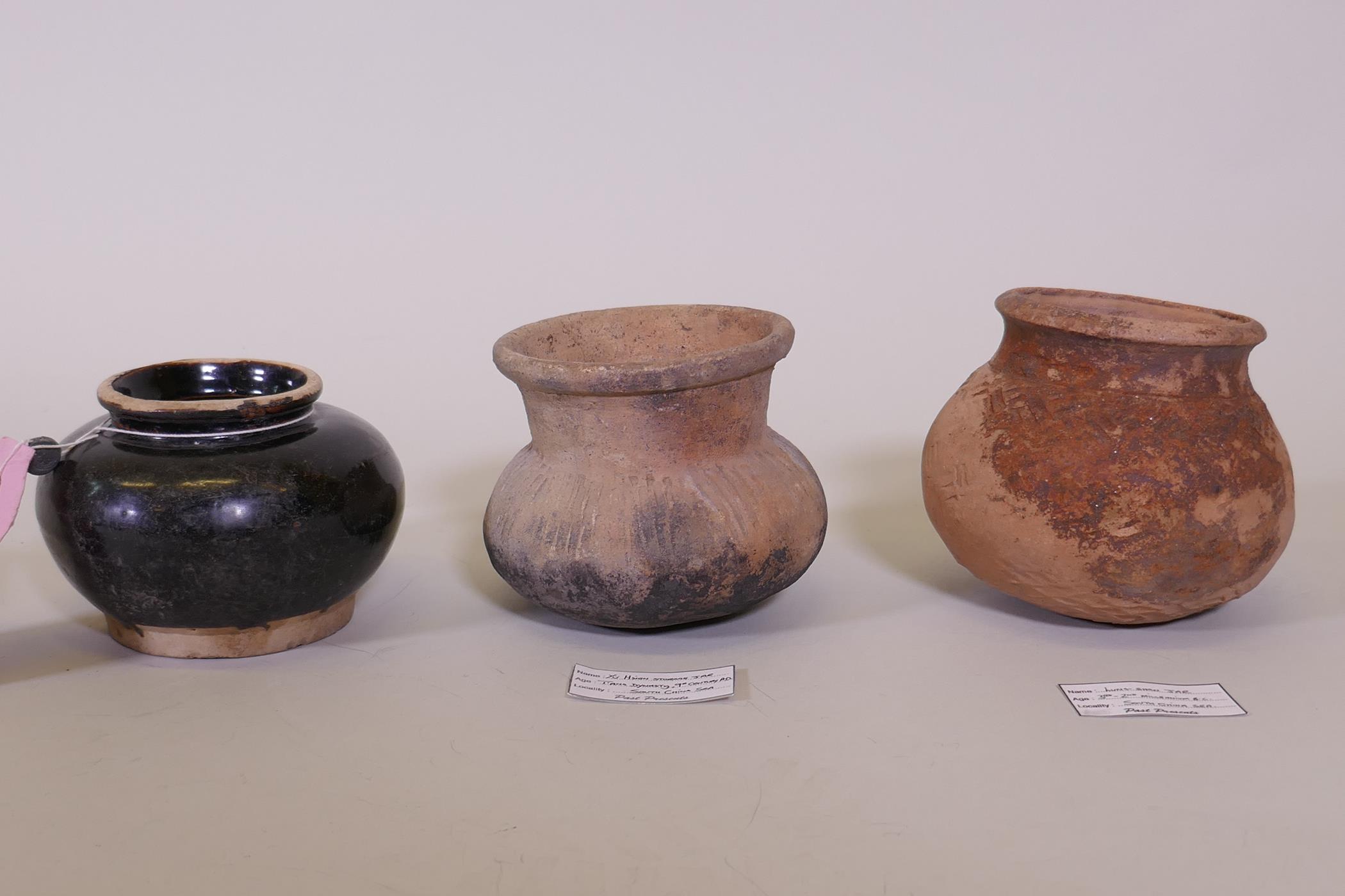 A Chinese Tang dynasty terracotta pot, labelled Hu Xian storage jar, another jar, Longshan, labelled