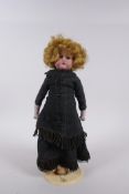 An antique German Armand Marseille bisque headed doll in a black dress, marked A.M. 370 9/0, 30cm