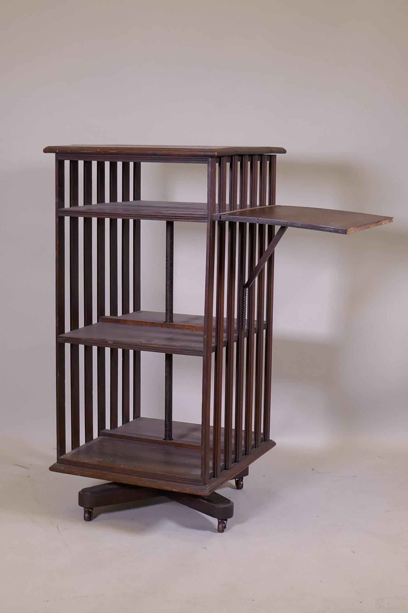 A Victorian oak revolving bookcase, three tiered with a ratcheted drop flap, raised on an iron base, - Image 2 of 4