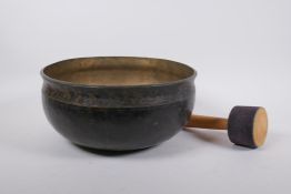 A large Tibetan bronze singing bowl with hammered finish and wood hammer, 13cm high x 28cm diameter