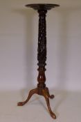 A mahogany torchere, raised on a carved column and tripod supports, 126cm high, 39cm diameter
