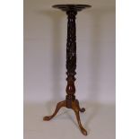 A mahogany torchere, raised on a carved column and tripod supports, 126cm high, 39cm diameter