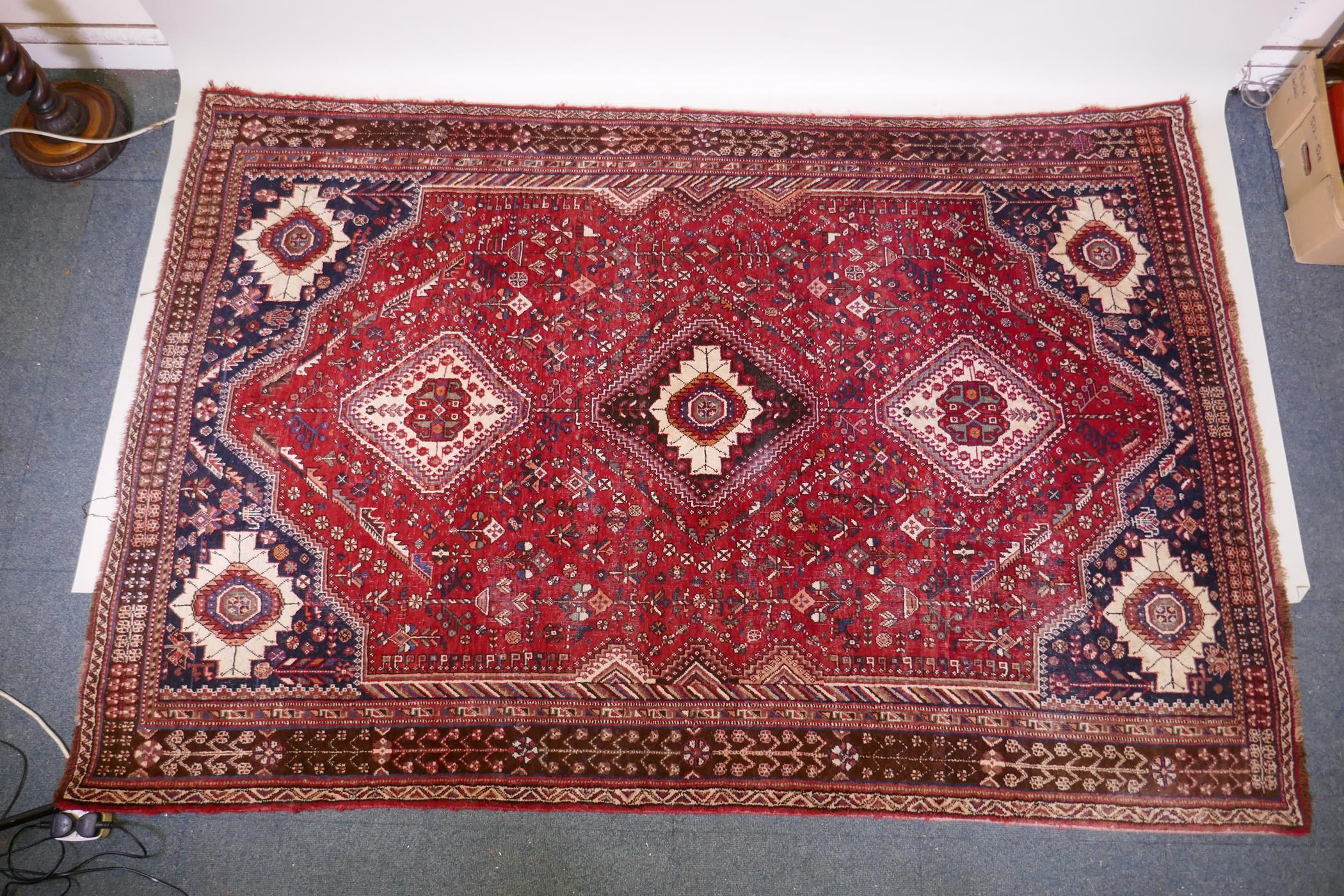 A hand woven red ground Persian carpet with a unique medallion design and chocolate brown borders,
