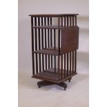 A Victorian oak revolving bookcase, three tiered with a ratcheted drop flap, raised on an iron base,