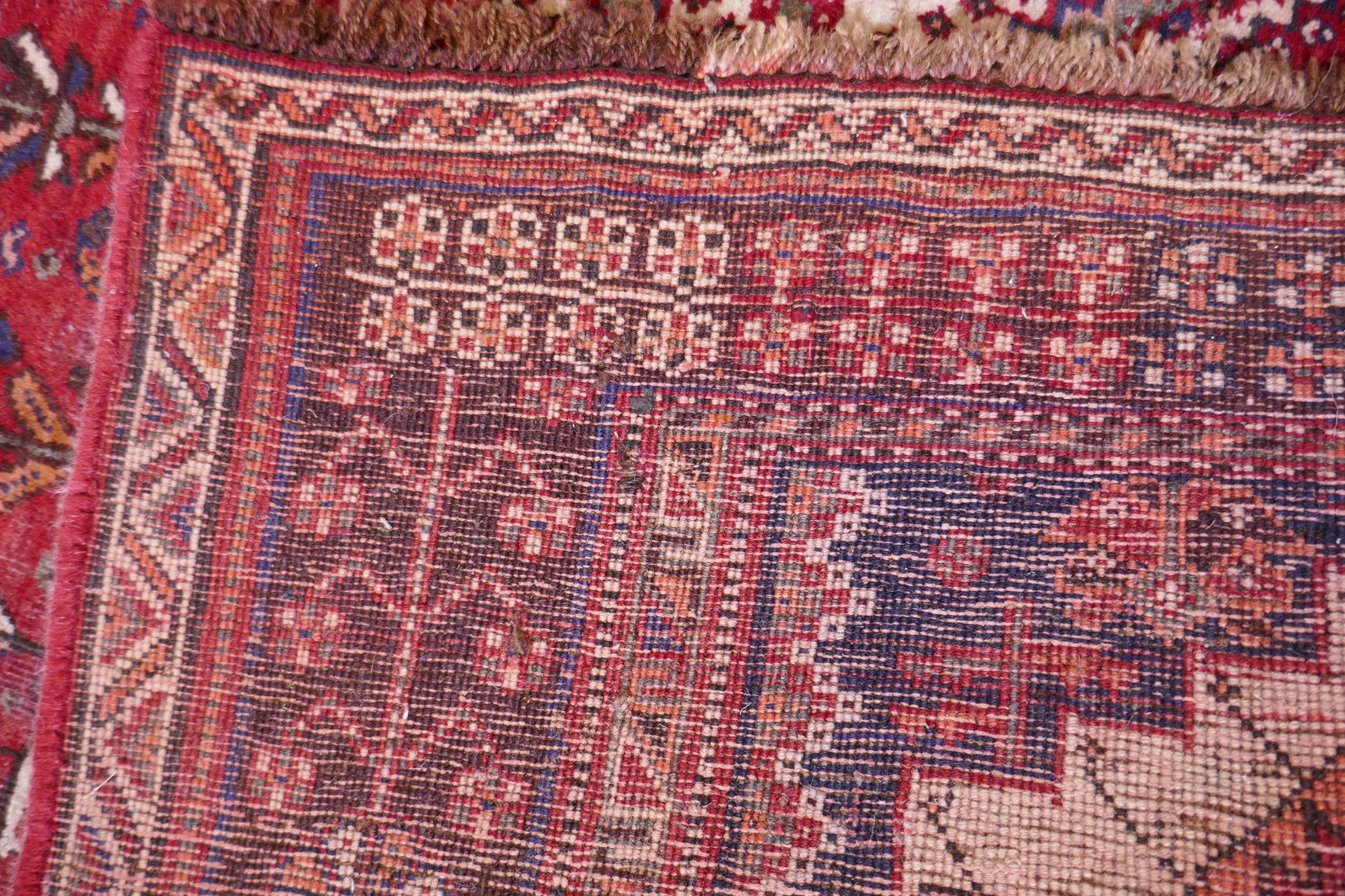 A hand woven red ground Persian carpet with a unique medallion design and chocolate brown borders, - Image 5 of 5