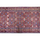 A hand woven red ground Persian Hamadan nomadic runner with an allover floral design, 102 x 310cm