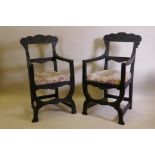 A pair of C19th ebonised X frame chairs with carved Green Man decoration and drop in seats