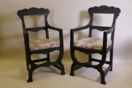 A pair of C19th ebonised X frame chairs with carved Green Man decoration and drop in seats