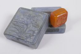 A Chinese hardstone box with carved lotus flower decoration to the cover, containing an amber