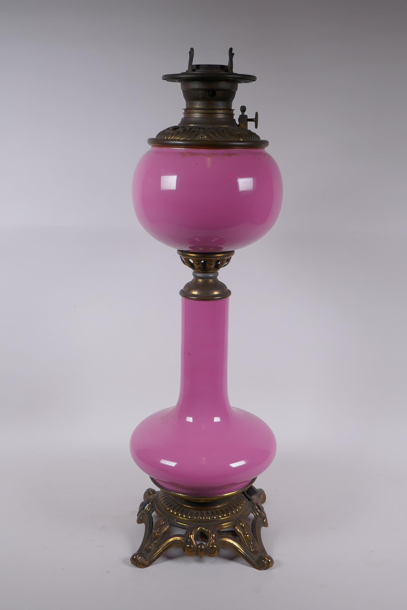 A pink glass and brassed metal oil lamp converted to electricity, 64cm high