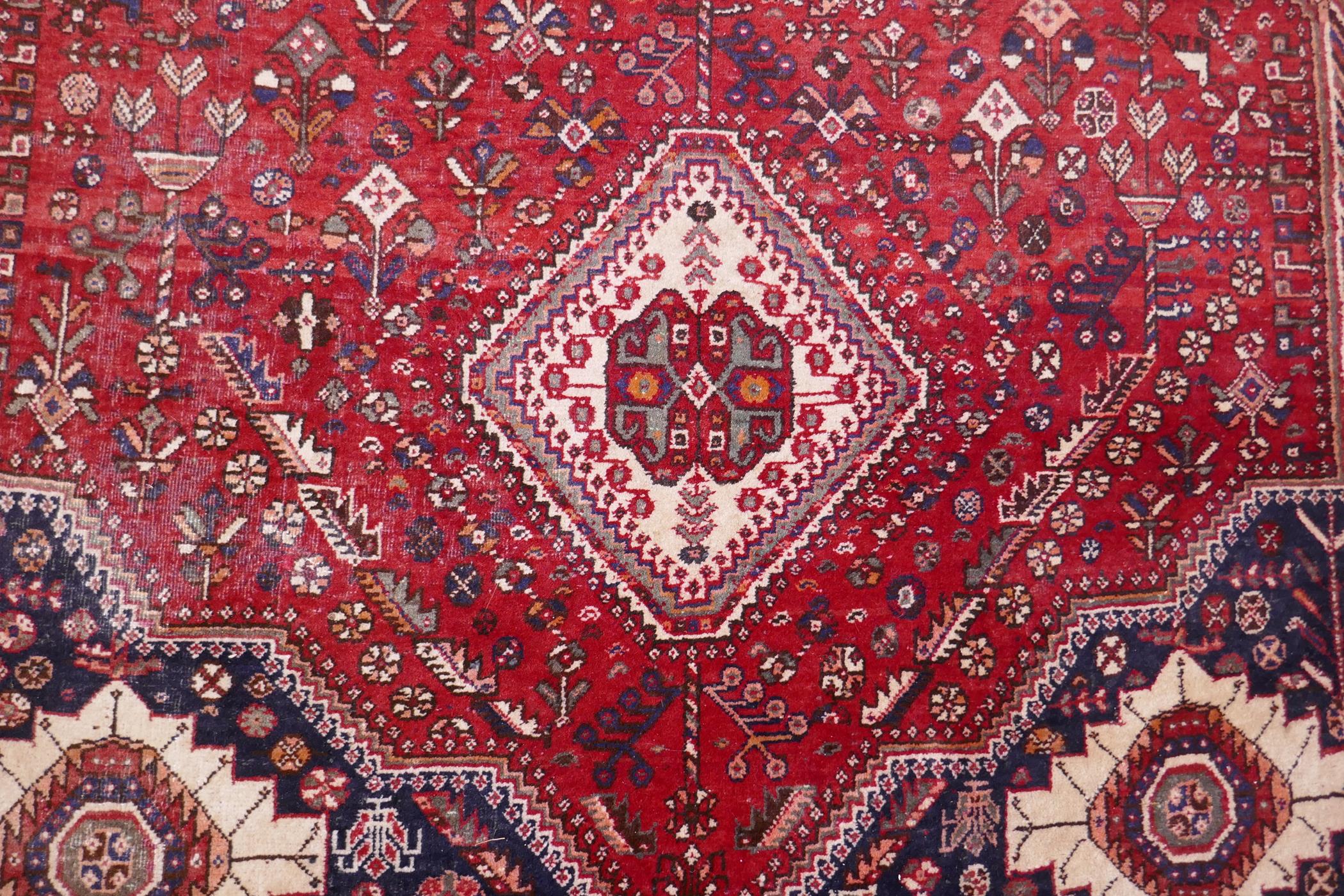 A hand woven red ground Persian carpet with a unique medallion design and chocolate brown borders, - Image 3 of 5