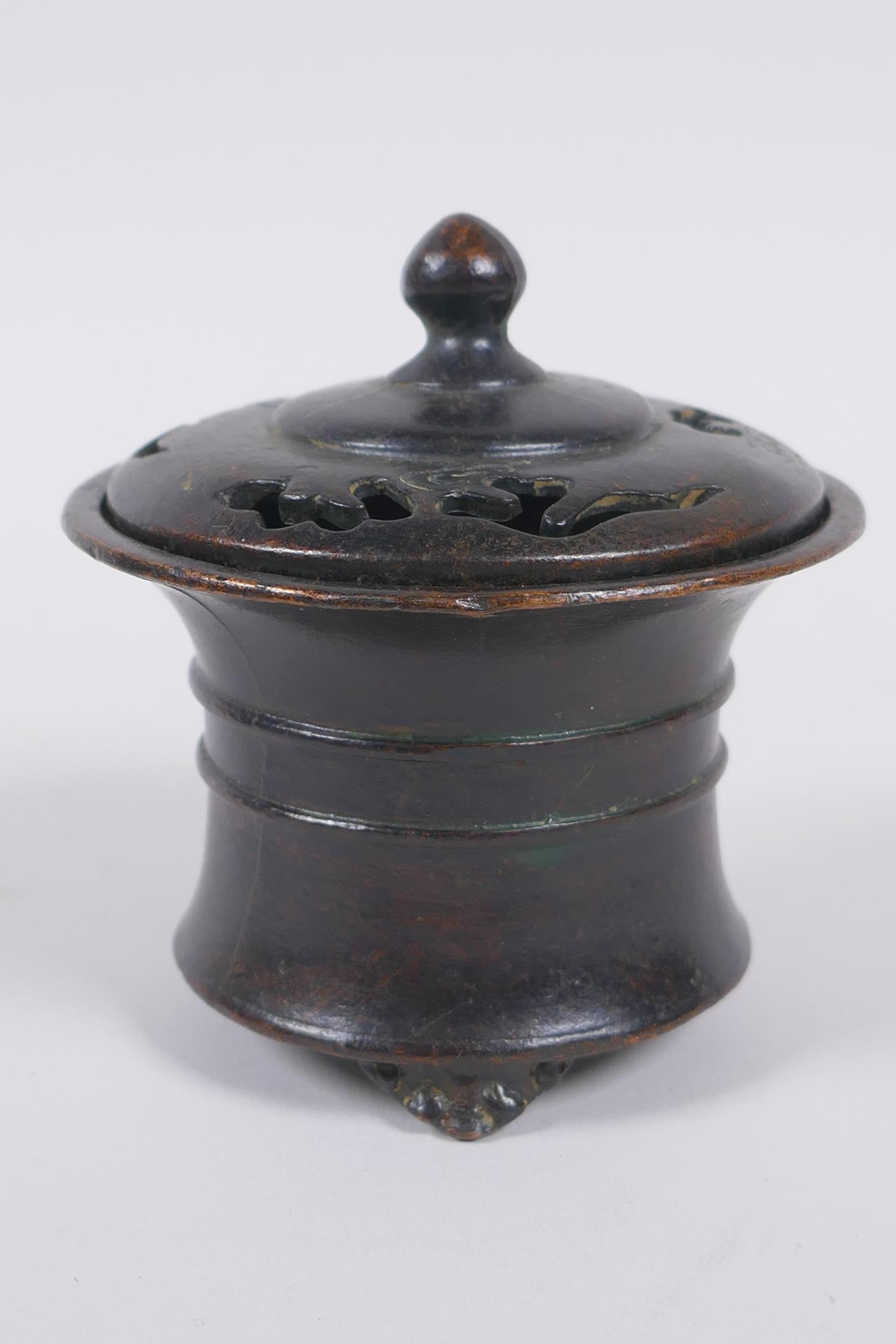A Chinese bronze censer and cover with a ribbed body and tripod supports, impressed seal mark to