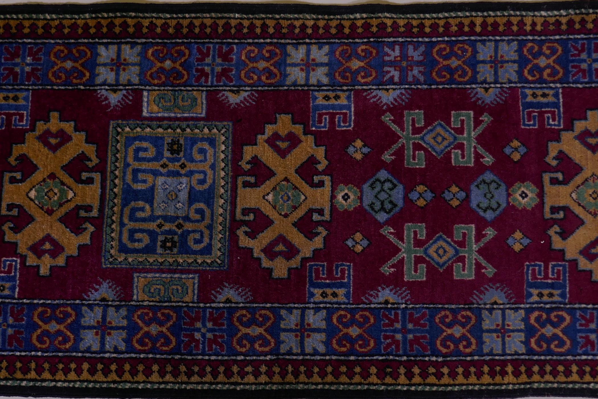 A claret wine ground wool caucasian runner with bespoke medallion design in unique colours, 322 x