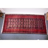A full pile hand woven red ground carpet with a geometric floral design, 268 x 130cm
