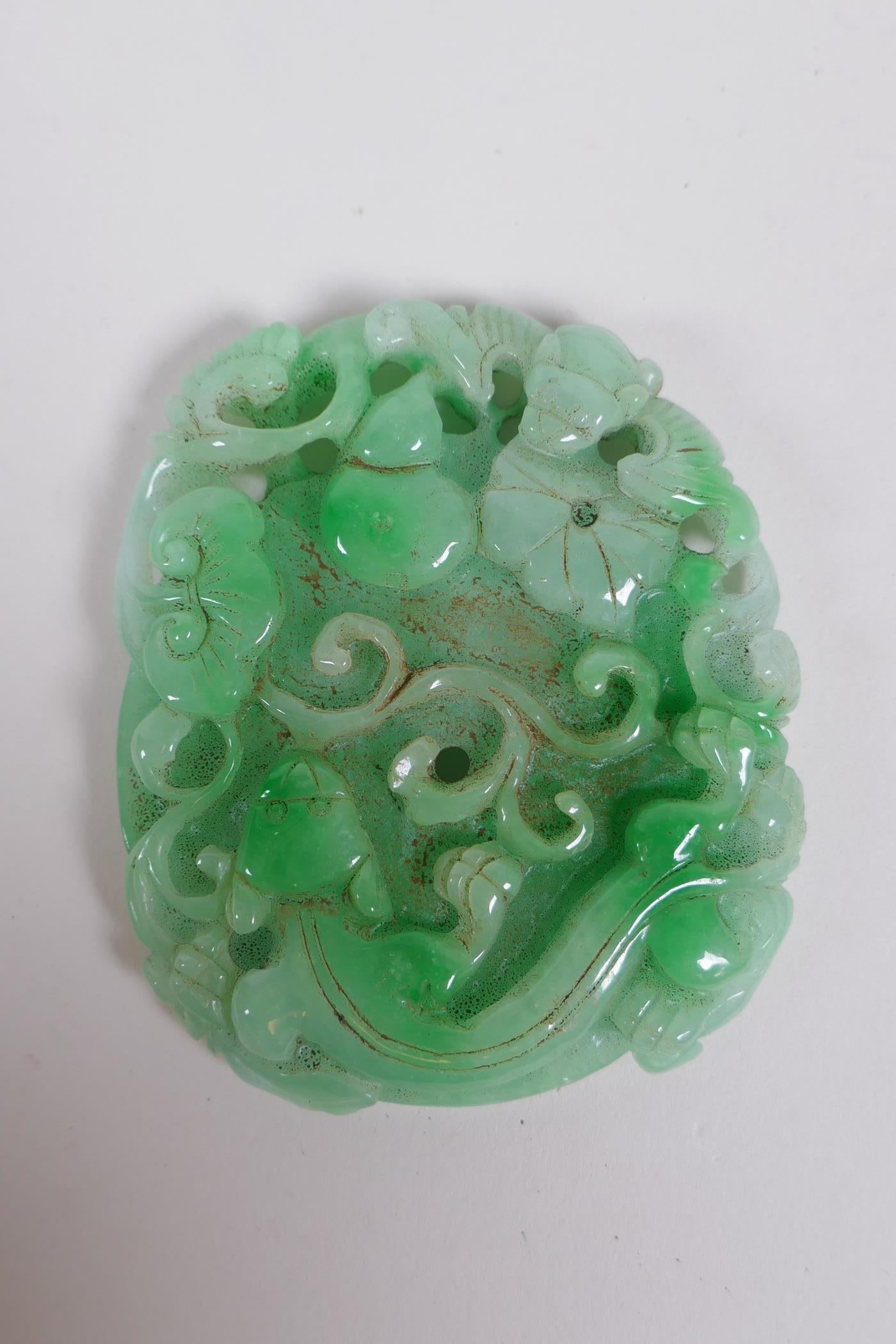 A Chinese carved mottled green jade pendant decorated with flowers, a gourd , kylin and pi disc, 7 x