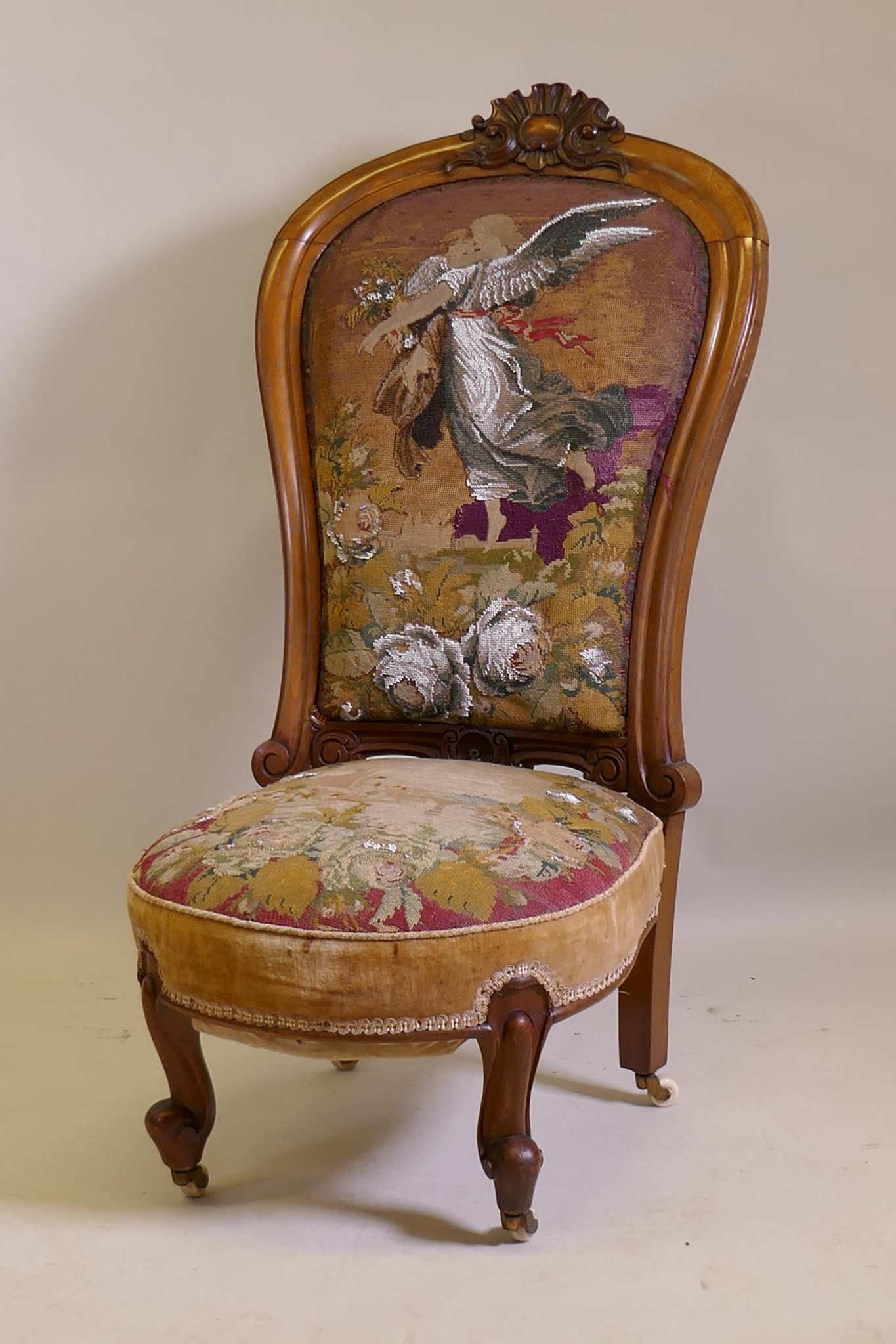 A Victorian walnut nursing chair with carved crest and shaped back, beadwork upholstery, raised on