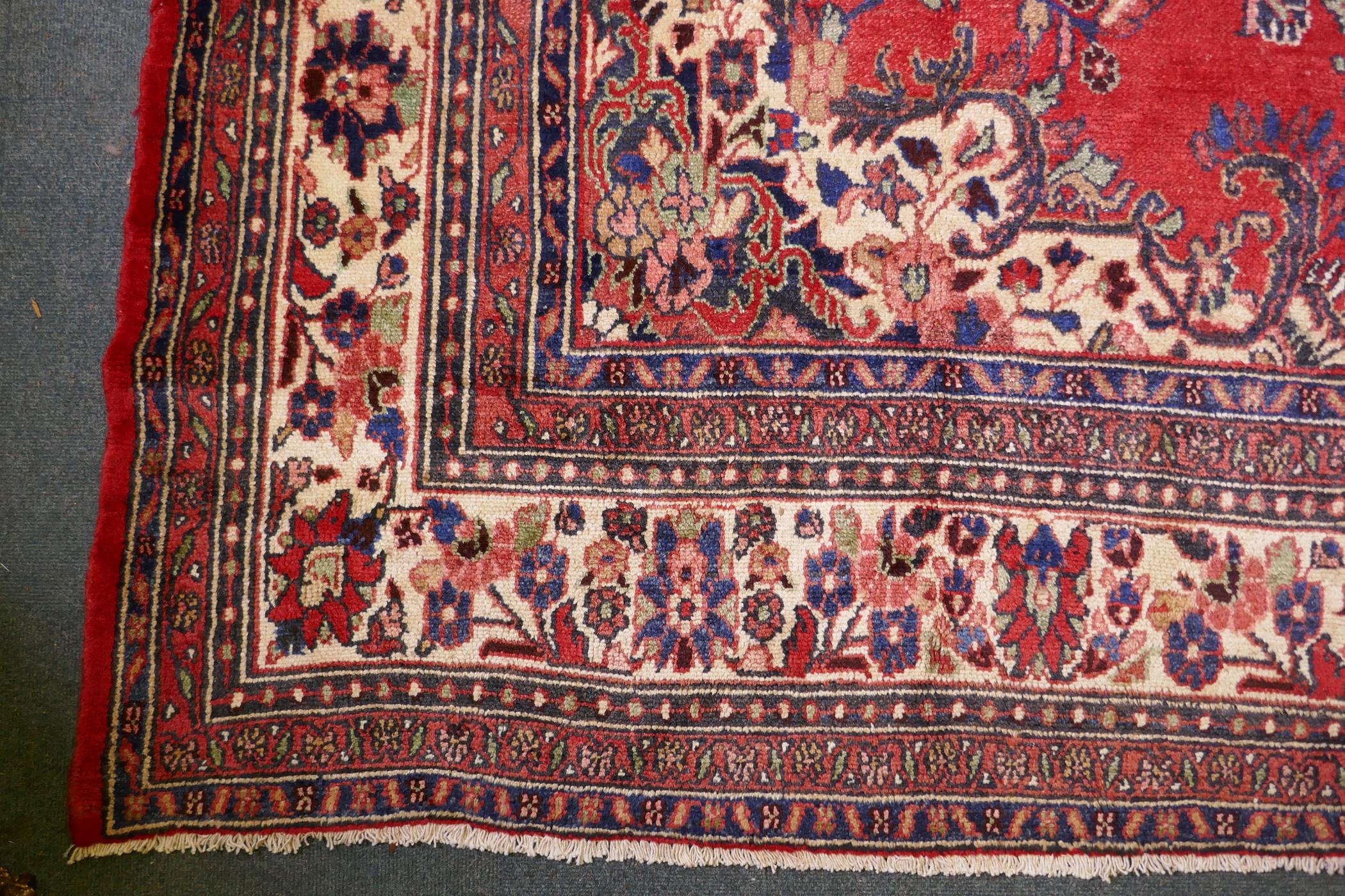 A Persian full pile red ground hand woven Sarouk village carpet with a floral medallion pattern - Image 5 of 6