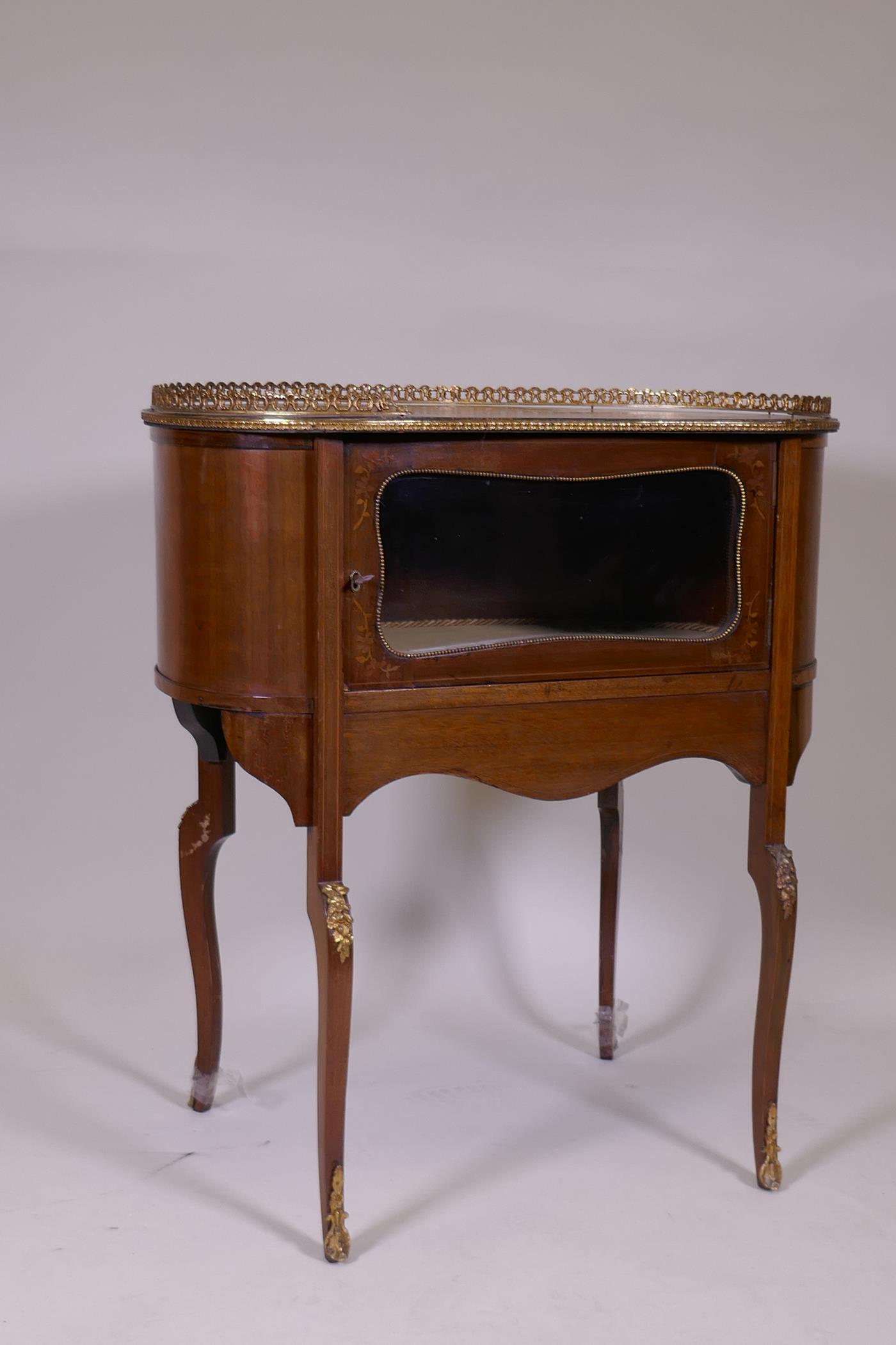 An inlaid mahogany kidney shaped vitrine, with pierced brass gallery top, single glazed door, raised