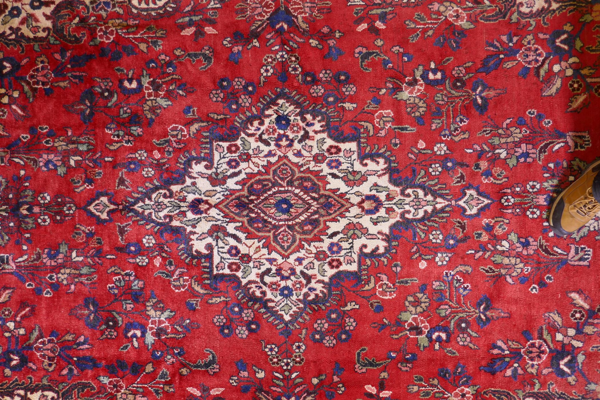 A Persian full pile red ground hand woven Sarouk village carpet with a floral medallion pattern - Image 3 of 6