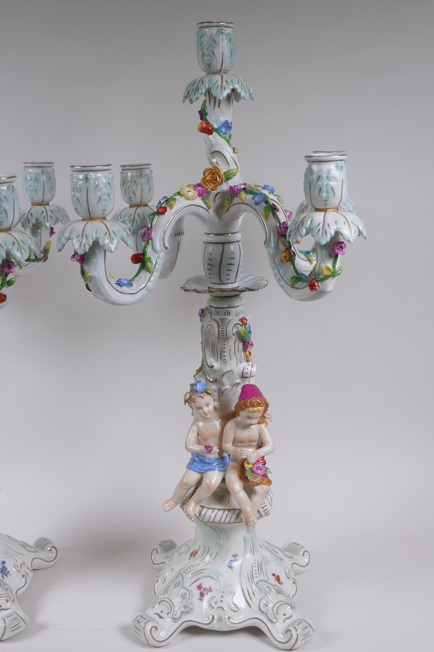A pair of continental porcelain four branch candelabra decorated with putti, 59cm high - Image 4 of 8