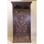 A C19th oak hall cupboard with single door over a drawer and carved decoration in the Renaissance